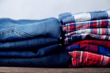 ahşap arka plan üzerinde kareli gömlek ve pantolon yığını.