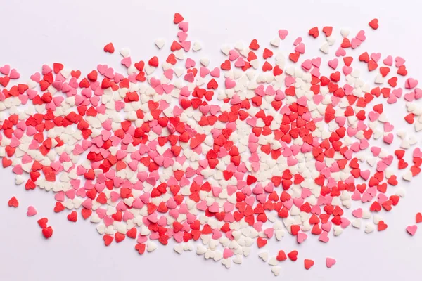 Dolci a forma di cuore rossi, rosa e bianchi sparsi su sfondo bianco. spazio per il testo. posa piatta — Foto Stock