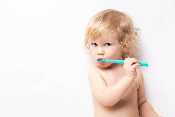Retrato de caucasiano pouco bonito encaracolado bebê limpa os dentes no fundo branco — Fotografia de Stock