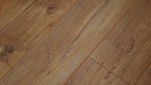 A câmera se move ao longo do chão, coberto com parquet laminado com uma textura de madeira marrom . — Vídeo de Stock