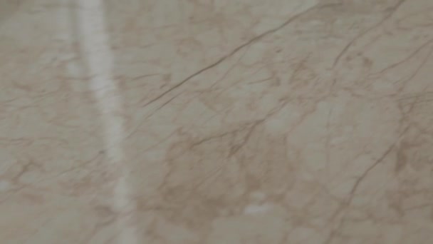La caméra se déplace en douceur le long d'une tuile de sol en céramique beige dans la maison à la lumière du jour. texture des carreaux de sol gros plan — Video