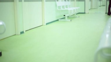Hastalar ve doktorlar hastane koridorunun alçak açısında yürüyorlar. vestibüle hastanede ayaklar yeşil tonlarında yakın.
