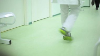 Hastalar ve doktorlar hastane koridorunun alçak açısında yürüyorlar. vestibüle hastanede ayaklar yeşil tonlarında yakın