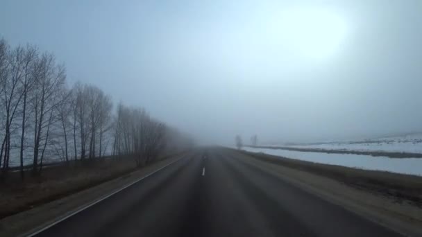 Coches en la carretera en la niebla. El mal tiempo y el tráfico peligroso de automóviles en la carretera. Carretera gris brumosa, coches conduciendo desvaneciéndose en la niebla . — Vídeos de Stock