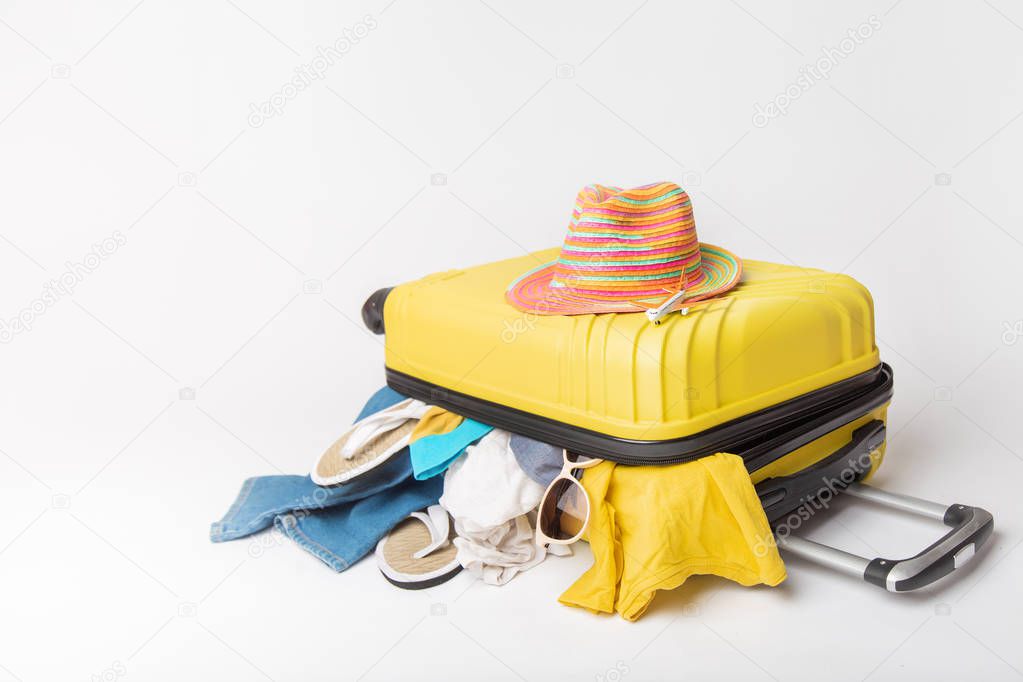 hat on a yellow suitcase with things of the traveler on a white background. concept rush travel fees