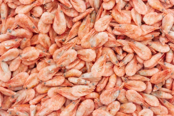 Pink fresh frozen shrimps with ice in a supermarket or fish shop. Uncooked seafood close up background. Fresh frozen prawns, delicacies, sea food concept,