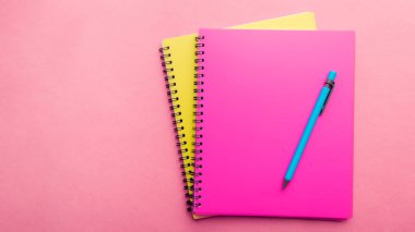 pembe arka plan üzerinde mavi kalem ile iki Not defteri pembe ve sarı. Metin için yer. Not Sayfası