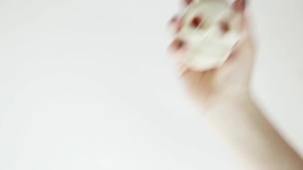 Mano caucásica femenina con uñas negras sostiene y aprieta un cráneo antiestrés sobre un fondo blanco . — Vídeo de stock