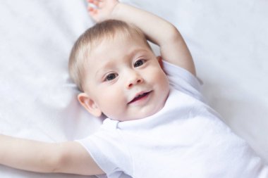 Sevimli erkek bebek beyaz tişörtü karanlık yatak odasında. Çocuk yatakta dinleniyor. Çocuklar için tekstil ve yatak. 