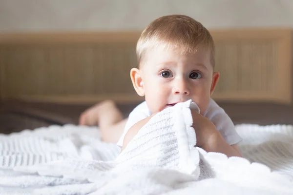Retrato de um bebê rastejando em uma cama com um cobertor no quarto — Fotografia de Stock