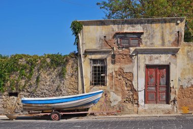 Eski evin yanında bir arabası üzerinde bir balıkçı teknesi. Rhodes, Yunanistan
