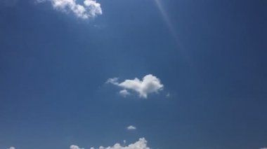 Beyaz bulutlar güneşin altında mavi gökyüzü üzerinde kaybolur. Hızlandırılmış hareket bulutlar mavi gökyüzü arka plan. Beyaz bulut ve güneş mavi gökyüzü.