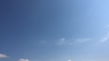 Beyaz bulutlar güneşin altında mavi gökyüzü üzerinde kaybolur. Döngü zaman atlamalı hareket bulutlar güzel bir mavi gökyüzü tarafından desteklenen özellikleri. Hızlandırılmış hareket bulutlar mavi gökyüzü arka plan ve güneş.