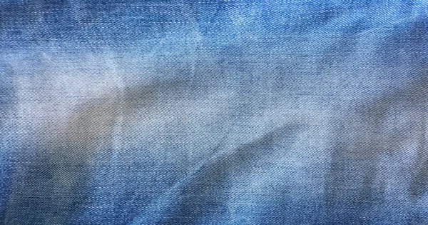 Blauwe jeans van gewassen denim textuur, blauwe achtergrond. — Stockfoto