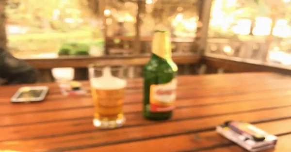 清空木桌的顶部, 有模糊的柜台酒吧和瓶子啤酒的背景. — 图库照片