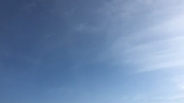 Beyaz bulutlar güneşin altında mavi gökyüzü üzerinde kaybolur. Döngü zaman atlamalı hareket bulutlar güzel bir mavi gökyüzü tarafından desteklenen özellikleri. Hızlandırılmış hareket bulutlar mavi gökyüzü arka plan ve güneş.
