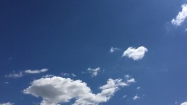 Mavi gökyüzündeki sıcak güneşte beyaz bulutlar kaybolur. Hızlandırılmış hareket bulutları, mavi gökyüzü arkaplanı ve güneş.