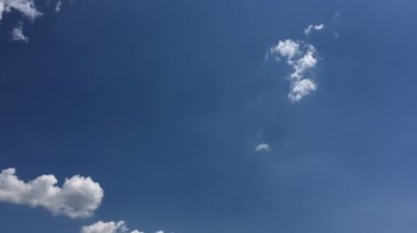 Mavi gökyüzündeki sıcak güneşte beyaz bulutlar kaybolur. Hızlandırılmış hareket bulutları, mavi gökyüzü arkaplanı ve güneş