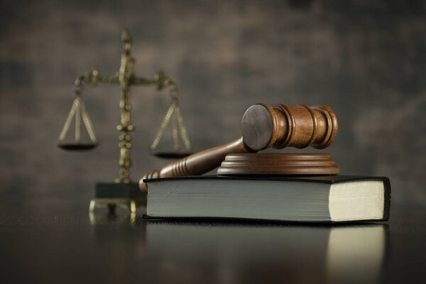 wooden gavel and book, themis scales of justice on background