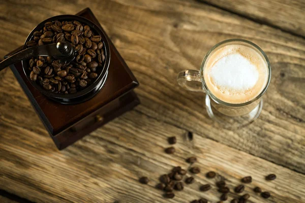 vintage coffee-grinder with roasted coffee beans and cup of coffee on wooden table