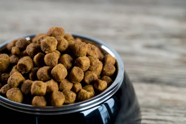 pile of dry dog food in bowl on wooden floor
