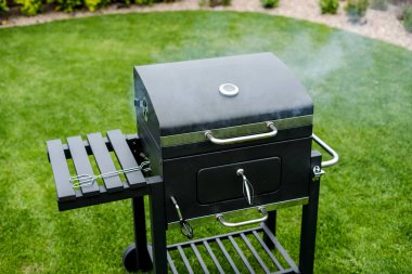 Yeşil çimenler üzerinde duran duman ile ızgara yakın