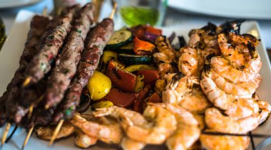 Izgara kebaplar, karidesler ve tabakta sebzeler.