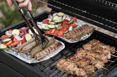 ızgarada yemek pişiren adam, şişler ve sebzeler üzerinde et