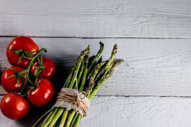 Sağlıklı taze yeşil kuşkonmaz ile ahşap arka plan domates