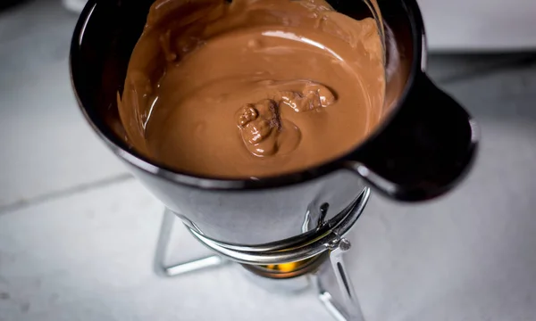 溶けたミルクチョコレートの小さな黒いバケツ — ストック写真