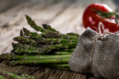 Sağlıklı taze yeşil kuşkonmaz ile ahşap arka plan domates