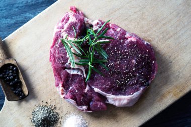 karabiber, tuz ve biberiye ahşap tahta üzerinde yemek pişirmek için hazır taze çiğ et parçası