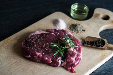 karabiber, tuz ve biberiye ahşap tahta üzerinde yemek pişirmek için hazır taze çiğ et parçası