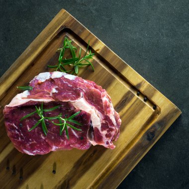 Çiğ otlar ile kara tahta üzerinde biftek et parçası