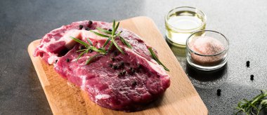 karabiber, tuz ve biberiye ahşap tahta üzerinde yemek pişirmek için hazır taze çiğ et parçası