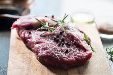 karabiber ve biberiye ahşap tahta üzerinde yemek pişirmek için hazır taze çiğ et parçası