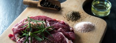 karabiber, tuz ve biberiye ahşap tahta üzerinde yemek pişirmek için hazır taze çiğ et parçası