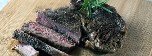 Appetizing sliced steak on chalkboard with herbs