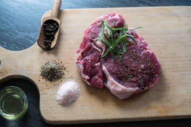 karabiber, tuz ve biberiye ahşap tahta üzerinde yemek pişirmek için hazır taze çiğ et parçası