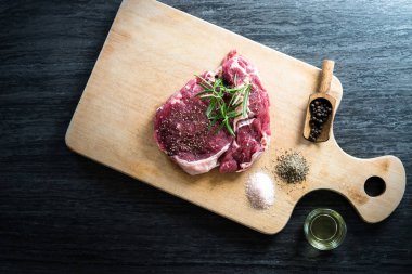karabiber, tuz ve biberiye ahşap tahta üzerinde yemek pişirmek için hazır taze çiğ et parçası
