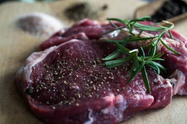 karabiber ve biberiye ahşap tahta üzerinde yemek pişirmek için hazır taze çiğ et parçası