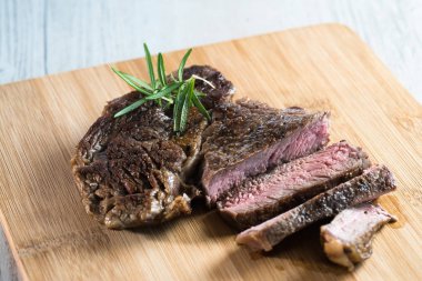 Otlar, tuz ve yağ ile kara tahta üzerinde biftek dilimlenmiş apetisant