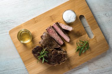 Otlar, tuz ve yağ ile kara tahta üzerinde biftek dilimlenmiş apetisant