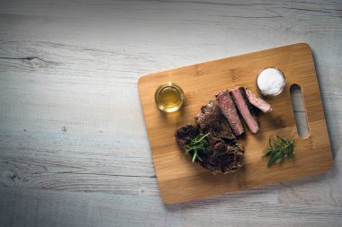 Otlar, tuz ve yağ ile kara tahta üzerinde biftek dilimlenmiş apetisant
