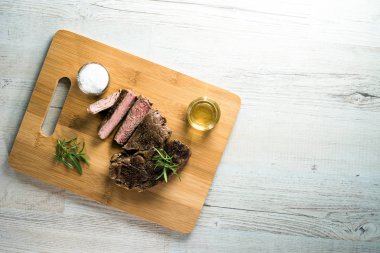 Otlar, tuz ve yağ ile kara tahta üzerinde biftek dilimlenmiş apetisant
