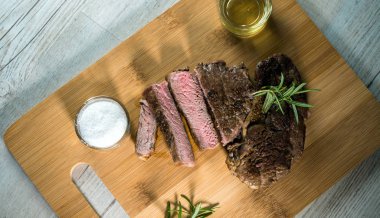 Otlar, tuz ve yağ ile kara tahta üzerinde biftek dilimlenmiş apetisant