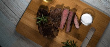 Otlar, tuz ve yağ ile kara tahta üzerinde biftek dilimlenmiş apetisant