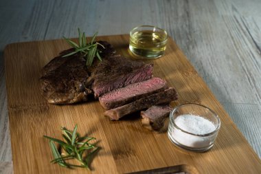 Otlar, tuz ve yağ ile kara tahta üzerinde biftek dilimlenmiş apetisant