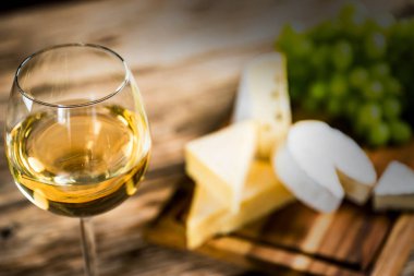 Ahşap arka planda üzüm ve şarap ile iştah açıcı peynir