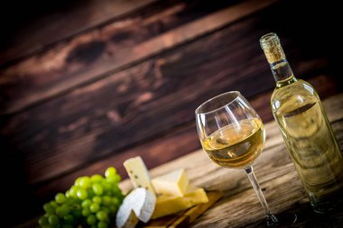 Ahşap arka planda üzüm ve şarap ile iştah açıcı peynir